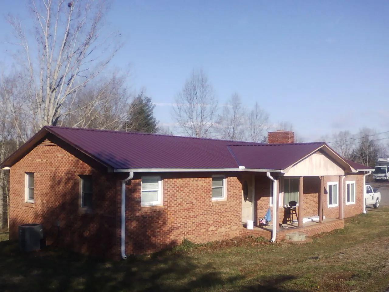 Burgundy metal roof on a brick ranch home with a new addition in Utica