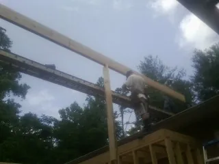 Carpenter setting a ridge beam over a new addition frame — Ice Dam Removal by Roofing Brothers in Utica